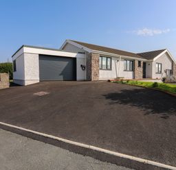 A single story house with a large driveway and a garage at Corrie Knowe in Trearddur Bay
