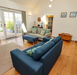 A living room with a sofa and ottoman at Little Tern in Seahouses