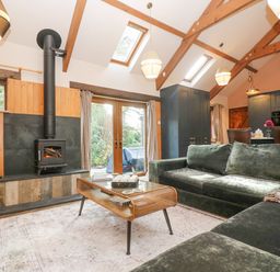 A living room with a woodburner stove green sofas and a wooden coffee table at Harveys House in Helston