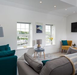 A sitting room with sofas chairs a lamp a side table and a wall mounted tv at Chy Lowen in Porthleven