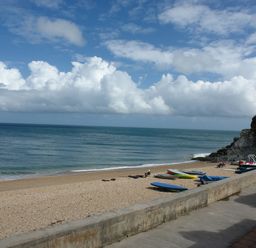A beach with boats on the sand and a seawall under a partly cloudy sky at 2 Bayview in Torcross