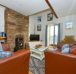 A living room with leather sofas wood burning stove and a view of the sea at 2 Bayview in Torcross