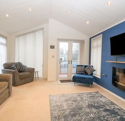 A living room with armchairs a wall-mounted television and a fireplace at Y Caban in Brynsiencyn