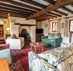A living room with wooden ceiling beams sofas and a fireplace at The Long House in Penmachno