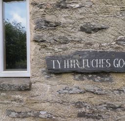 Window with a slate sign on stone wall at The Long House in Penmachno