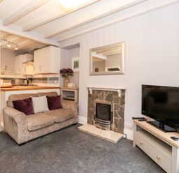 A living room with a sofa near a fireplace and a TV on a stand at Fell View in Ambleside