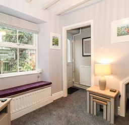 A room with a window seat a television nested tables with a lamp and two framed pictures on the walls at Fell View in Ambleside