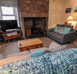 A living room with two sofas cushions a wooden coffee table a fireplace and a television at The Haven in North Sunderland near Seahouses