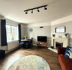 A living room with a table and chairs and a television at Melanie's Cottage in Brewers Quay Harbour