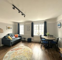 A living room with a sofa and dining table at Melanie's Cottage Brewers Quay Harbour