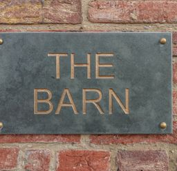 A metal sign with the words THE BARN mounted on a brick wall at The Barn Helperby near Boroughbridge