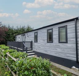 A mobile home with a deck and steps at Heather William Lodge near Woodhall Spa