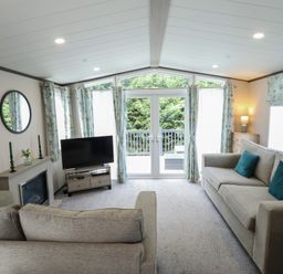 A living room with a sofa, television, and sliding door at Heather William Lodge near Woodhall Spa