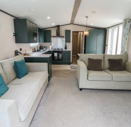 A living room with a sofa and kitchen area at Heather William Lodge near Woodhall Spa