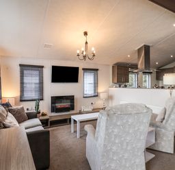 A living room with a sofa armchairs a TV and a fireplace at Evergreen Pines in Cayton Bay near Scarborough