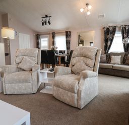 A living room with two armchairs a sofa a dining table and chairs and a floor lamp at Evergreen Pines in Cayton Bay near Scarborough