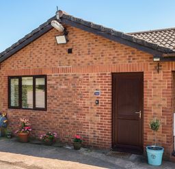A brick exterior of a property with a door and window at Piglet Corner in Culmstock