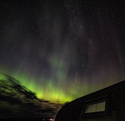 A night sky with stars and northern lights above a building roof at Heisgeir in Sollas Isle Of North Uist