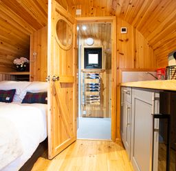 A wooden bedroom with a bed and a kitchenette at Heisgeir in Sollas Isle Of North Uist