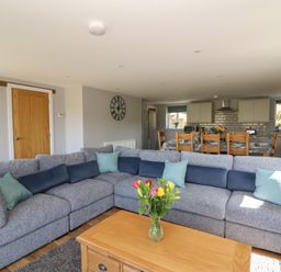 A living room with a grey sectional sofa and a wooden coffee table with flowers at Curtau Llanfaredd near Builth Wells