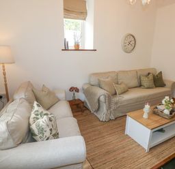 A living room with two beige sofas a wooden coffee table and a floor lamp at The Stables Near Solva