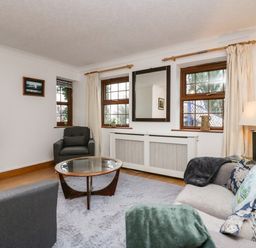 A living room with gray chairs a glass coffee table and a sofa with pillows and blankets at Time and Tide in Arnside