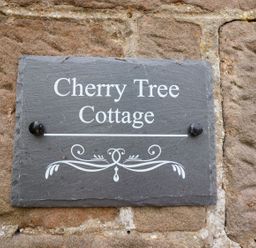 A stone plaque with Cherry Tree Cottage written on it attached to a stone wall at Cherry Tree Cottage in Fallodon near Embleton