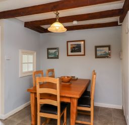 A dining room with a wooden table and four chairs under exposed beams at Cherry Tree Cottage in Fallodon near Embleton