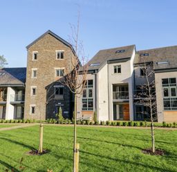 A modern residential building with stone and plaster exterior surrounded by grass and young trees at Brimstone in Backbarrow near Ulverston
