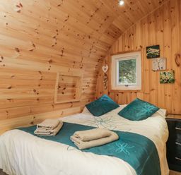 A bedroom with a bed towels bedside table and window at The Poddy in Bushton near Lyneham
