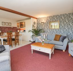 A living room with gray sofas a wooden coffee table and a dining table with chairs at Woodland View in Muddiford near West Down