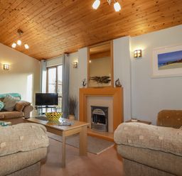 A living room with sofas a coffee table a television and a fireplace at 4 The Glade in St Minver