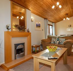 A living room with a fireplace sofa coffee table and dining table at 4 The Glade in St Minver