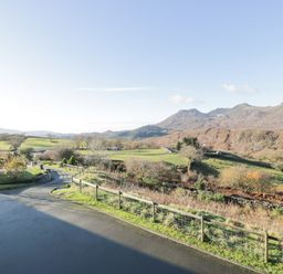 A rural landscape with a road fence and hills in the background at Y Tylwyth in Blaenau Ffestiniog