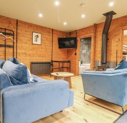 A snug with blue sofas and a wood stove at Otter's View in South Luffenham near Edith Weston