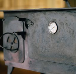 A close-up of a metal wood-burning stove with a temperature gauge and handle at Beech in Dalwood