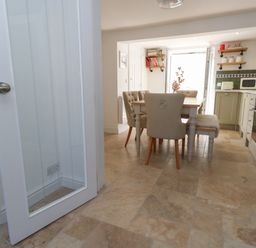 A kitchen with a dining table and chairs a microwave oven and shelves with jars at Belvedere Cottage in Weymouth