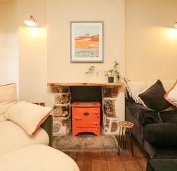 A living room with two sofas and a small stove in a fireplace at Josie in Pentewan