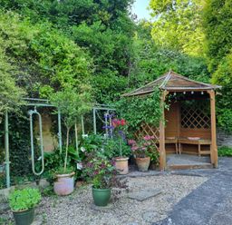 A garden with a gazebo and potted plants at Anvil Cottage in Gatcombe near Blakeney