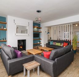 A living room with gray sofas wooden tables fireplace and shelving at 2A Front Street in Embleton