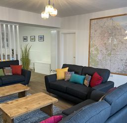 A sitting room with black sofas and wooden coffee tables with a large map on the wall at 2A Front Street in Embleton