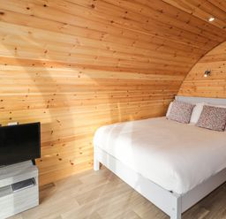 A bedroom with a bed pillows and a television on a stand at The Wheelhouse Pod No 2 in Burtonport County Donegal