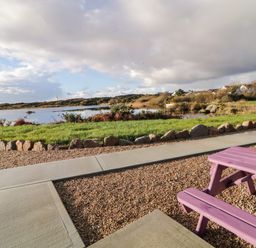 A picnic table near a pond with rocks and grass at The Wheelhouse Pod No 9 in Burtonport County Donegal