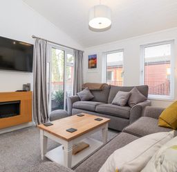 A living room with two gray sofas a wooden coffee table a wall-mounted tv and an electric fireplace at Bowness Bay Lodge Oakside 16 Fallbarrow Park near Bowness-On-Windermere
