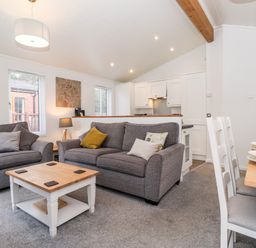 A living room with two grey sofas a wooden coffee table and a dining table with chairs at Bowness Bay Lodge Oakside 16 Fallbarrow Park near Bowness-On-Windermere