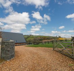 An outdoor view of a property entrance with a gravel driveway at Valley View Hideaway in Ffostrasol