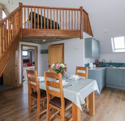 A kitchen with a dining table and staircase at Valley View Hideaway in Ffostrasol