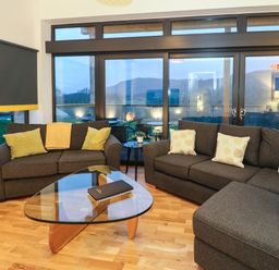 A living room with gray sofas and a glass coffee table in front of large windows at 2 Strathtay Lodges in Aberfeldy