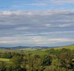 A landscape with rolling green hills and trees under a partly cloudy sky at South Holm in Moreleigh