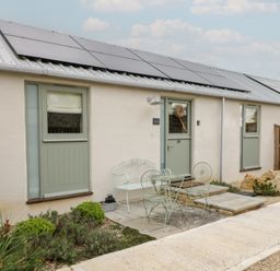 An outdoor area with a door, windows, table, and chairs at The Little Loft in Burford